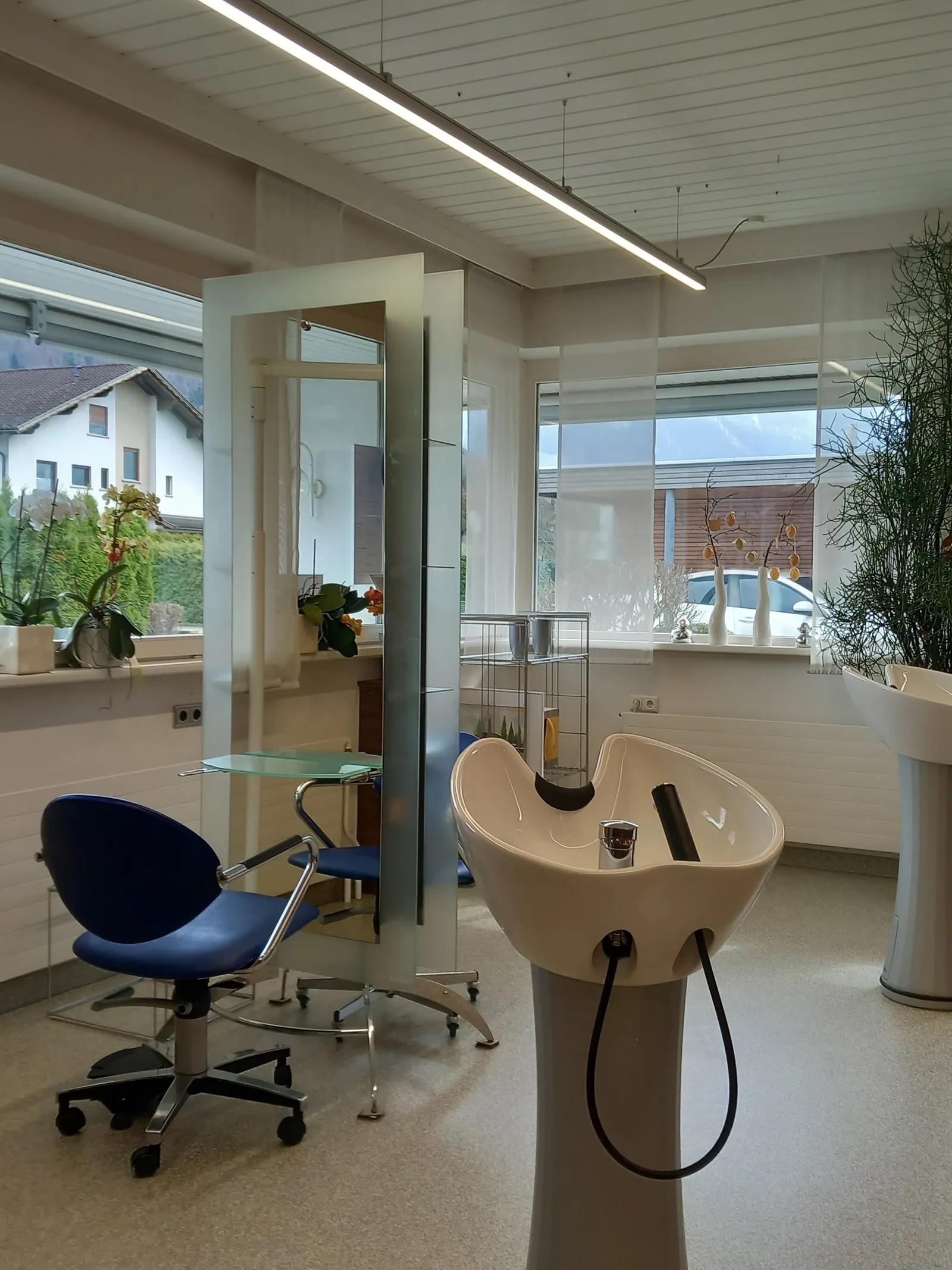 Heller Salonbereich mit Waschplatz und Friseurstuhl