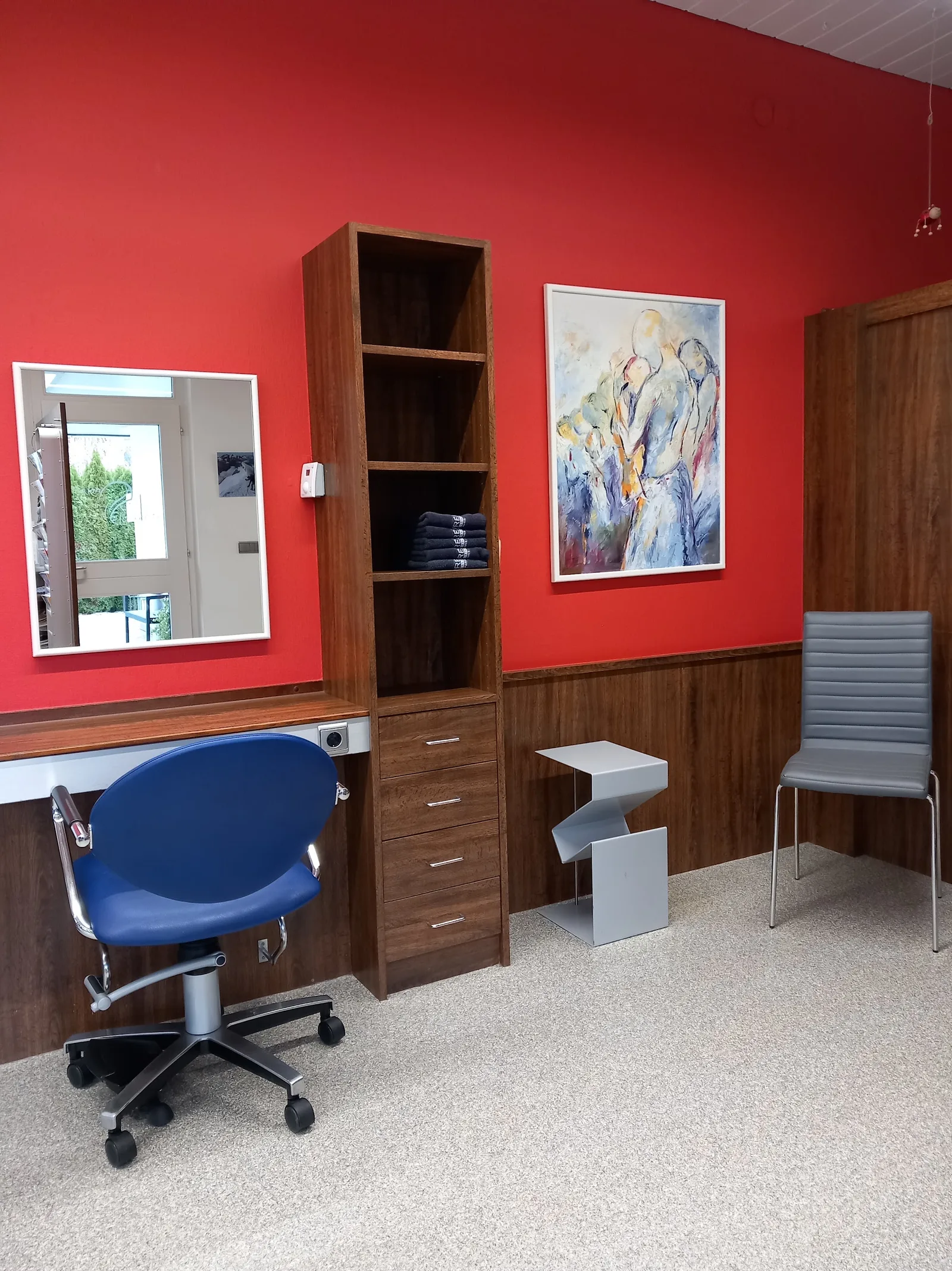 Friseurstuhl vor roter Wand mit abstrakter Kunst